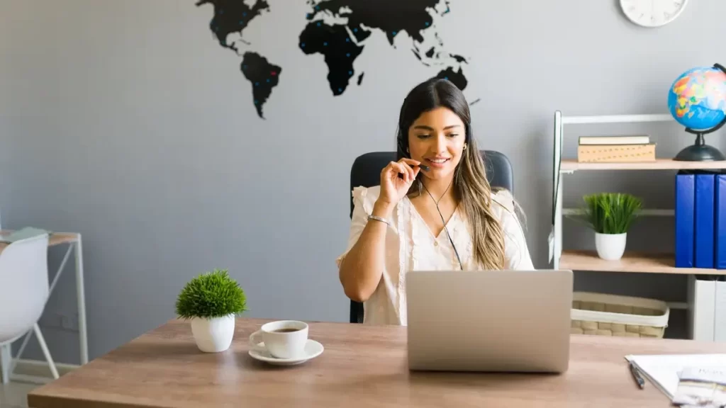 Imersão em Inglês - Executiva no seu escritório trabalhando no computador e falando no celular.