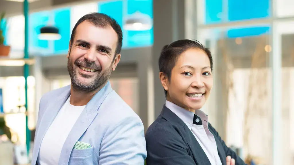 Mulher asiática gestora de empresa. Homem americano alta liderança. Ambos sorriem - representando que possível hamonia entre liderança asiática e liderança americana.