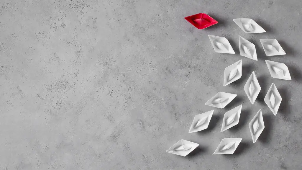 Barcos de papel em branco com um barco a frente vermelho. Representando o papel da comunicação e liderança