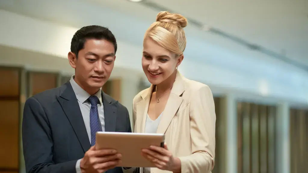 Casal de executivos. Executiva loira representando liderança americana. E homem asiático representando a liderança asiática.