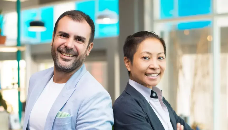 Mulher asiática gestora de empresa. Homem americano alta liderança. Ambos sorriem - representando que possível hamonia entre liderança asiática e liderança americana.